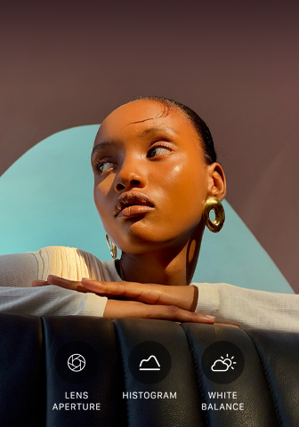 Nahaufnahme eines gut beleuchteten Models mit einem bunten Hintergrund, das das Pro Kamera-System mit der Pro Steuerung zeigt: Blende, Histogramm, Weissabgleich